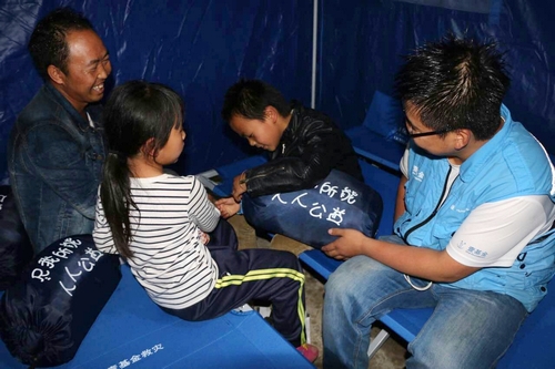 壹基金联合救灾-贵州联合救援工作人员将折叠床和睡袋送到受灾家庭手中