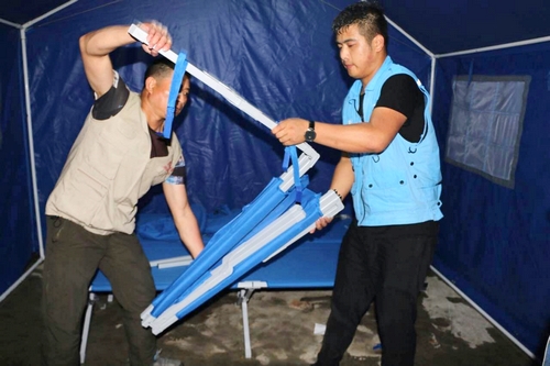 壹基金联合救灾-贵州联合救援的工作人员将折叠床送到受灾群众手中